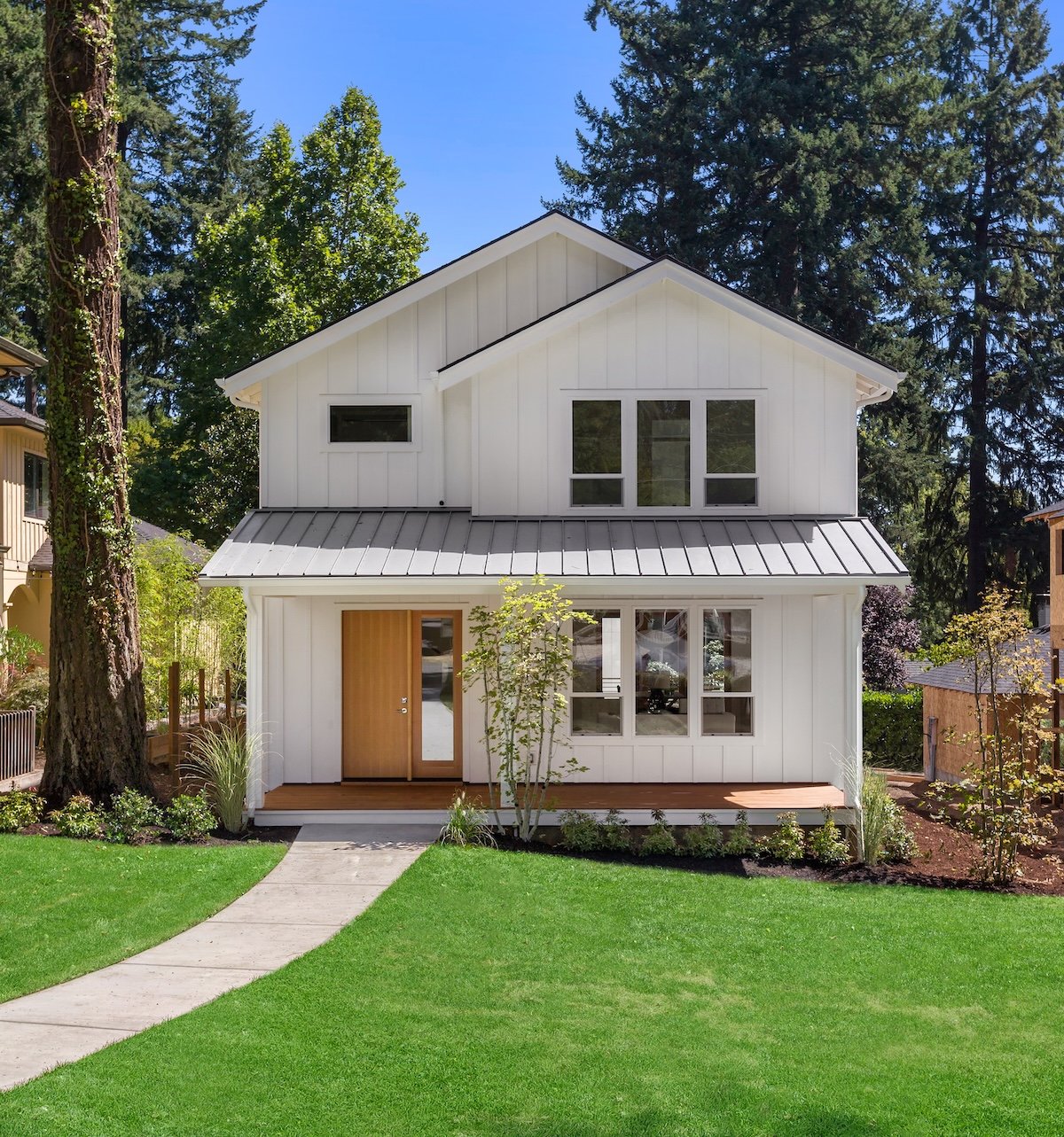 New house with white siding, gray metal roof, and clean landscaping