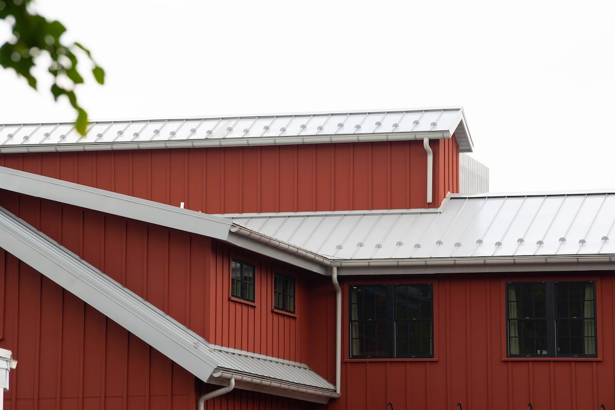 modern standing seam metal roof on red house.