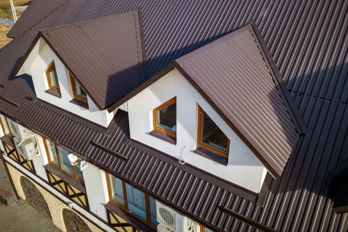 Close-up aerial view of building attic rooms exterior on metal shingle roof