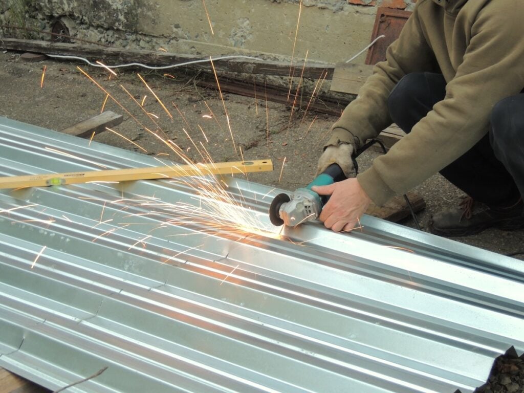 A worker cuts corrugated metal roofing