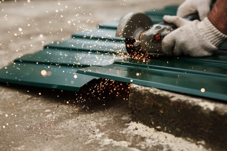 Roofer cuts green metal roofing with small saw