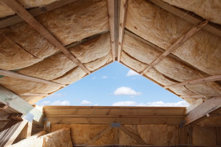 Fiberglass insulation installed in the sloping ceiling of a new frame house.