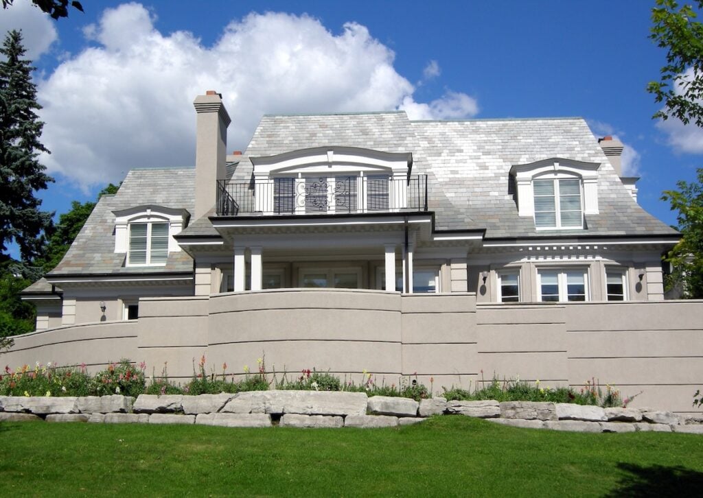 House on hill with retaining wall and white light color slate roof