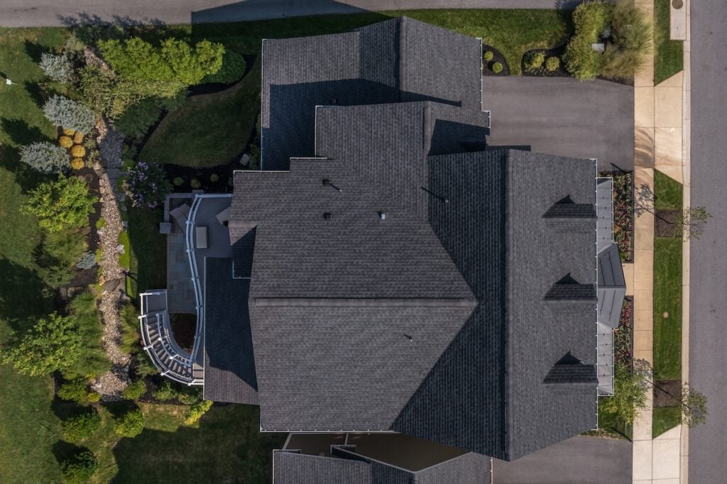 Aerial top down view of a complex hip and valley pitched roof with three dormers on a new construction American luxury single family house
