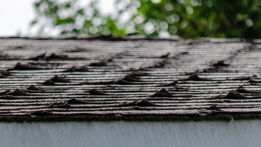Close-up of curled roofing shingles on a residential rooftop