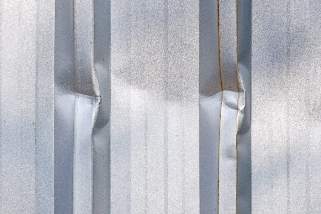 Close up dents on surface of corrugated metal roofing
