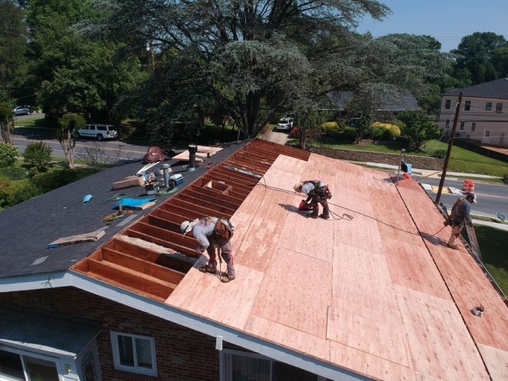 signs you need a roof replacement Springfield Roofing workers on top of house replacing roof