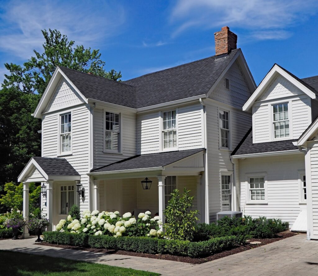white clapboard house with gable and portico entrance and white siding