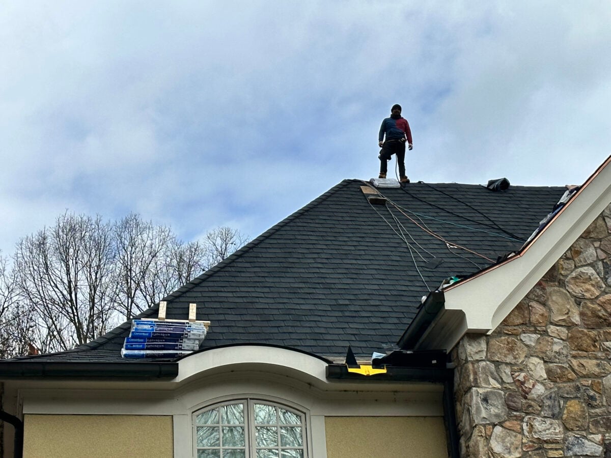 residential roof replacement services Springfield Roofing worker on top of shingles roof