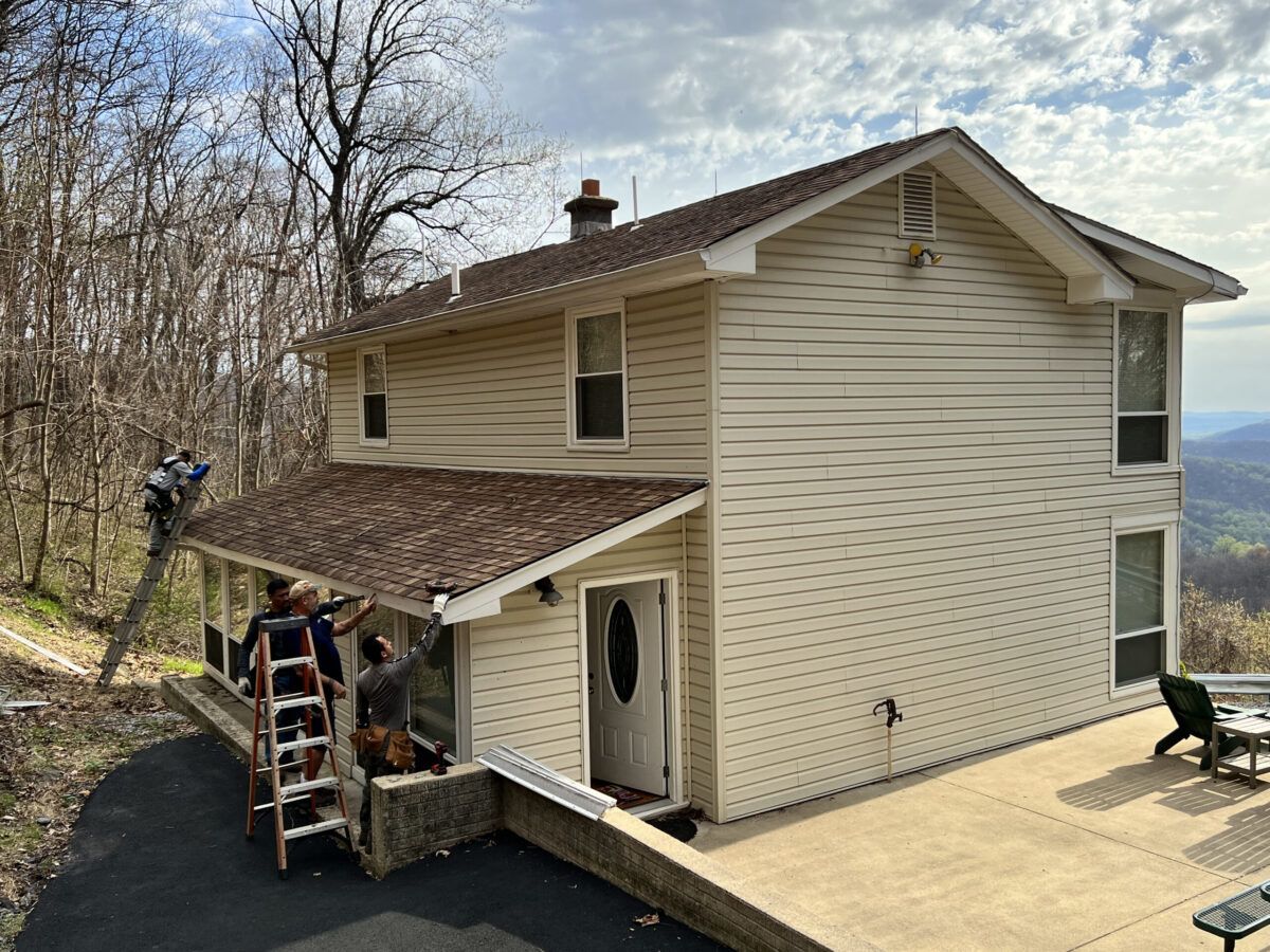 roof replacement process small house worker on top of shingles roof