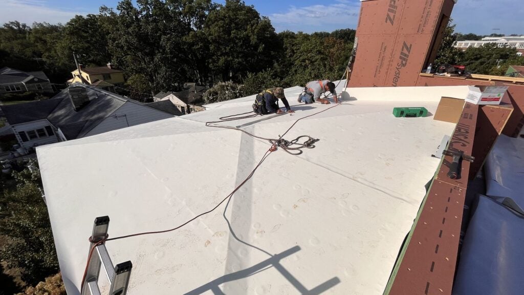 Roofing worker on top of shingles roof two workers replacing whole roof