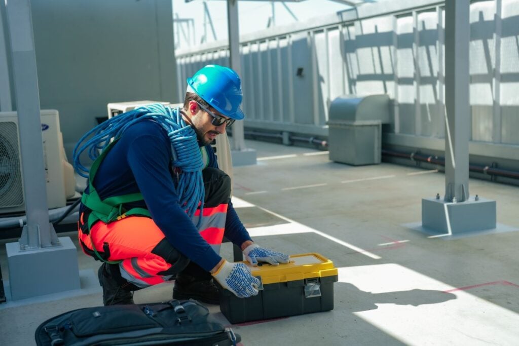 commercial roof maintenance checklist worker using toolbox and rope