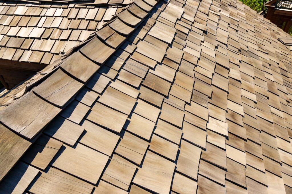 Wood shingle roof shows staggered cedar shake pattern in warm tones
