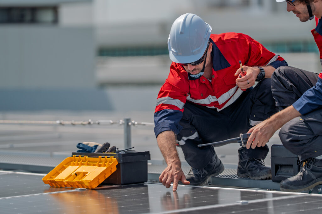 Two technicians inspecting solar panels during preventative roof maintenance