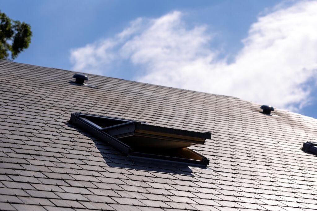 Open skylight window on gray slate tile roof