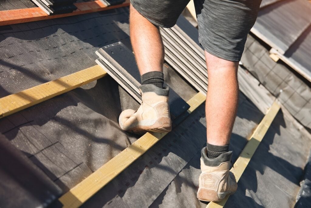 Roofer stepping across roof battens wearing lightweight work boots