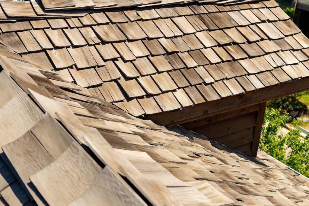 Cedar shake roof shingles cover two intersecting roof planes above a small dormer